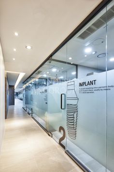 an empty office hallway with glass walls and signs on the wall that says implantt