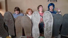 four people sitting in front of several pairs of shoes