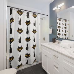 a bathroom with a shower curtain that has black cats on it and yellow eyes in the background