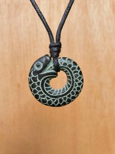 This ouroboros pendant is carved by myself. It's carved from stone called green granit. It's carved on the both sides.  The size of the pendant is approximately 3cm(1.1inches) in diameter.  The pendant comes with an adjustable black waxed cotton cord.  Not only are these pendants a beautiful thing to wear as part of your jewellery collection, but they are also very pleasing to the touch. The weight and smoothness of the hand carved stone makes these pendants a tactile comfort, as well as a one o Symbolic Green Engraved Necklaces, Green Carved Amulet Necklace, Green Engraved Amulet Jewelry, Green Carved Round Pendant Jewelry, Nature-inspired Carved Round Pendant Jewelry, Knots Jewelry, Serpent Necklace, Hand Carved Stone, Stone Engraving