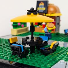 a lego table with an umbrella and some toys on it's top, including a toy car