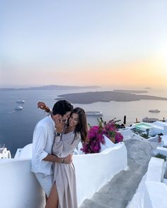 a man and woman standing next to each other near the ocean