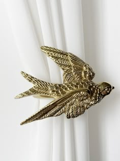 a gold bird brooch sitting on top of a white curtain