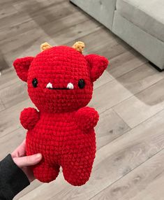 a hand holding a red crocheted stuffed animal