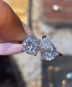 two diamond earrings being held up to the camera