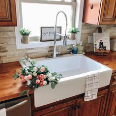 a white sink sitting under a window next to a wooden counter top in a kitchen