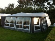 a large tent sitting on top of a lush green field next to trees and bushes