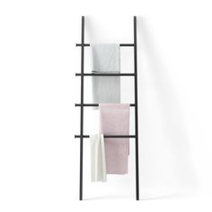 a black shelf with towels hanging from it's sides and two white ones on the other side