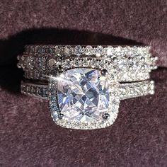 an engagement ring and wedding band set with a cushion cut diamond surrounded by round diamonds