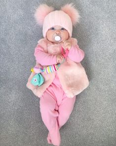 a baby doll with a pacifier in it's mouth laying on the floor