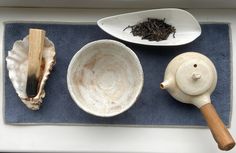 bowls and spoons are sitting on a blue towel next to some seashells