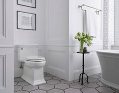 a white toilet sitting next to a bath tub in a bathroom with tile flooring