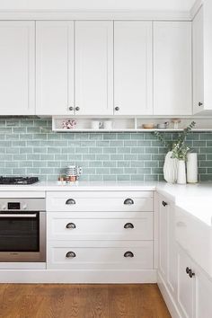 a kitchen with white cabinets and wood floors