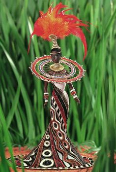 a figurine is standing in the grass with a red feather on it's head