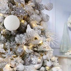 a white christmas tree with silver ornaments and snowflakes