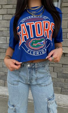 Calling all gators -- this tee is for YOU. This royal blue tee with the UF gator logo in the center is perfect for any game day coming up!! University of Florida licensed! Comes cropped or uncropped.  80% cotton, 20% polyester Model is 5'2" with a 34A bust, 25" waist, 34" hips, and wearing a size small. Model usually 2/4. This item runs true to size! Uf Gator, Gator Logo, University Of Florida, Blue Tee, Game Day, Royal Blue, Jade, Graphic Tees, University