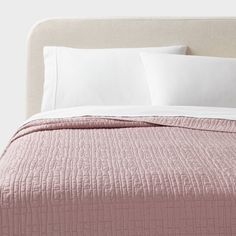 a bed with pink bedspread and white pillows