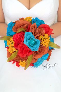 a bridal bouquet with red, orange and blue flowers in the bride's hand