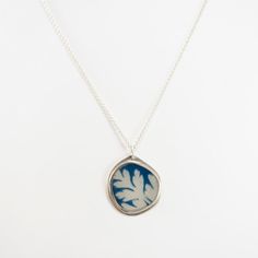 A Cyanotype photograph of a leaf are encased in a sterling silver frame and jeweler's resin, with sterling silver ear hooks. Jen's jewelry is limited edition and one-of-a-kind art jewelry made with her own or collected photography, fine metals, and resin. Says Jen, "I created my first collection of Photo-Jewelry nearly 20 years ago. This idea came to me as a direct result of my art school education at Pratt Institute, where I majored in photography and my work experience as a studio assistant. M Silver Square Pendant Jewelry, Silver Square Pendant Jewelry With Soldered Details, Silver Jewelry With Soldered Square Pendant, Silver Nature-inspired Jewelry, Etched Nature-inspired Silver Jewelry, Etched Silver Nature-inspired Jewelry, Nature-inspired Etched Silver Jewelry, Silver Jewelry With Large Pendant For Keepsake, Blue Leaf-shaped Jewelry Gift