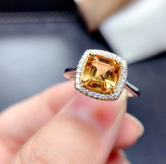 a person holding an orange and white diamond ring