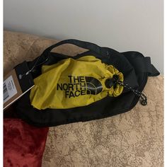 the north face fanny bag is on top of a couch with a tag attached to it