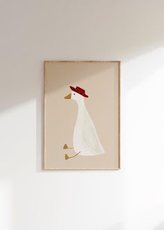 a white duck with a red hat on it's head hanging from a wall