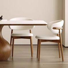 a dining table with two chairs and a vase on the floor in front of it