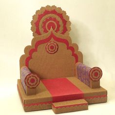 a chair made out of cardboard sitting on top of a white floor next to a red rug