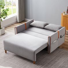 a modern daybed with two pillows on it in front of a window and rug