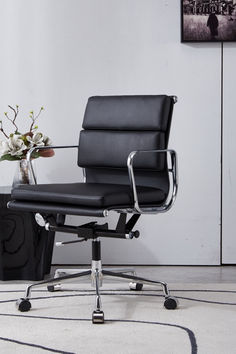 an office chair sitting on top of a rug next to a vase with flowers in it