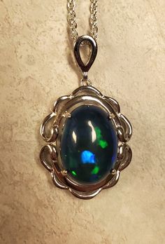 "Beautiful Blue And Green Flash Black Opal, 10.8x14.4mm, 4.8 Carat Ethiopian Smoked Opal, See Video! 925 Sterling Silver Frame Style Pendant, Rhodium Plated, 18\" Sterling Silver Chain. Chain Length Options Available By Messaging Seller At Time Of Purchase. Velvet Necklace Box Included." Formal Sterling Silver Cabochon Necklace, High Luster Blue Jewelry For Anniversary, Oval Sapphire Cabochon Necklace, Oval Sapphire Necklace With Cabochon Cut, Formal Blue Cabochon Necklace, Formal High Luster Blue Jewelry, Formal Blue High Luster Jewelry, Silver Oval Necklace With Bail, Silver Oval Cabochon Necklace For Formal Occasions