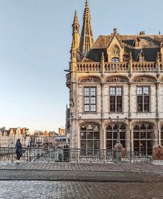 a large building with many windows and towers on it's sides in front of a cobblestone street