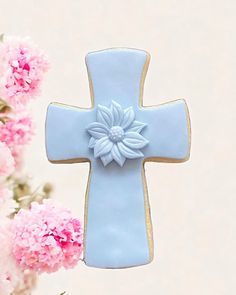 a blue cross decorated with flowers next to pink carnations