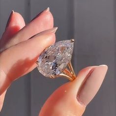 a woman's hand holding an oval shaped diamond in her left hand, with the center stone missing