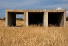 two concrete structures sitting in the middle of a field with tall grass on either side