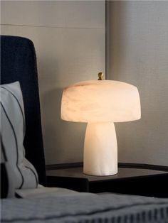 a white lamp sitting on top of a table next to a bed