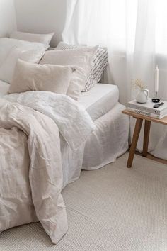 a bed with white linens and pillows in a small room next to a window