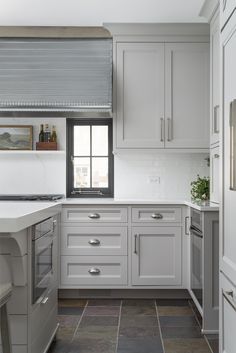 a kitchen with white cabinets and gray flooring