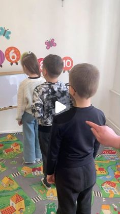 a group of children standing in front of a whiteboard