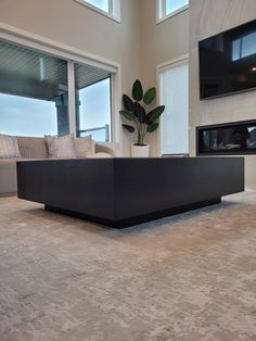 a living room with a large black couch in it's centerpiece and a television mounted on the wall