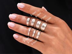 a woman's hand with five different sized rings on her fingers and measurements for each ring