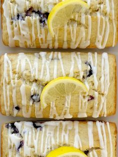 three lemon blueberry scones with icing and two lemons on top, one is cut in half