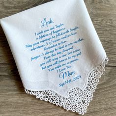 a white handkerchief with blue lettering on it sitting on top of a wooden table next to a pair of scissors