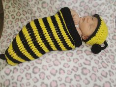 a newborn baby wearing a yellow and black striped hat