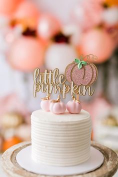 a little pumpkin cake topper sitting on top of a white cake