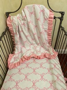 a baby crib with a pink and white comforter on it's side