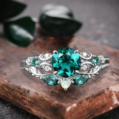 a green ring sitting on top of a wooden table next to some leaves and stones