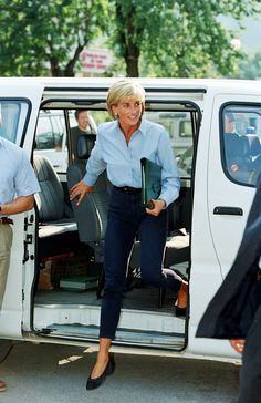 the woman is stepping out of the white van with her hand in her pocket and other people standing around