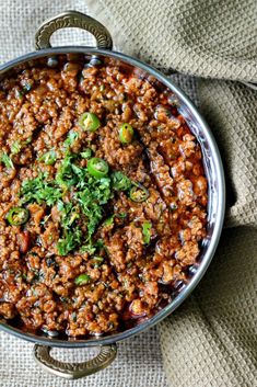 a large pot filled with meat and vegetables on top of a cloth covered tablecloth