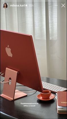 an apple computer sitting on top of a desk next to a cup and saucer